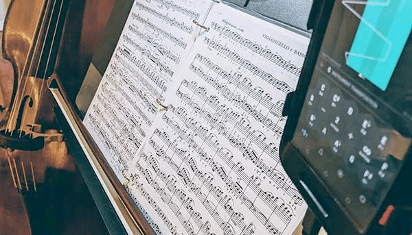 photo of a practice setup: double bass, sheet music, and tuner